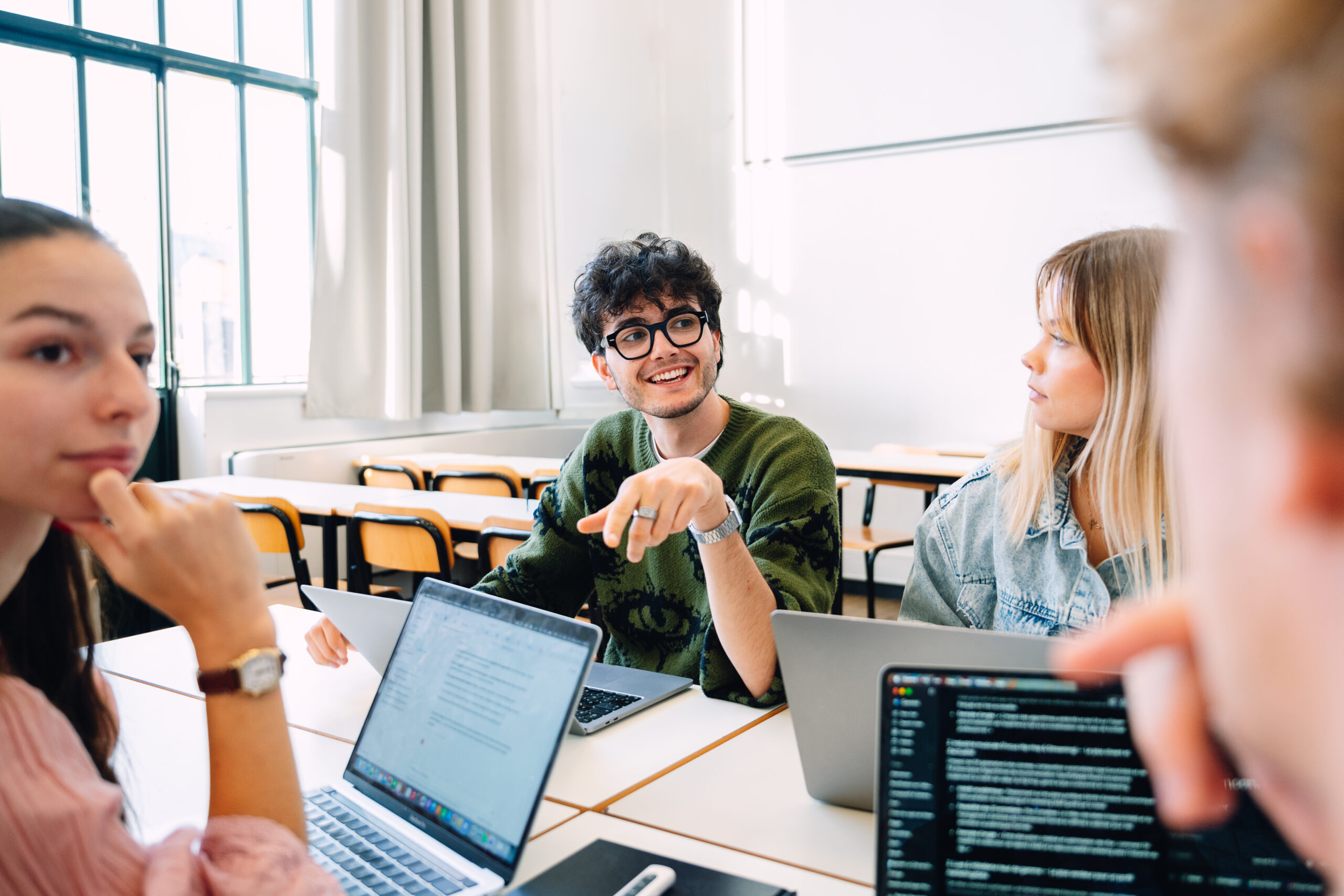 Participants concentrés devant leurs ordinateurs portables pendant un événement, l'un sourit à l'objectif