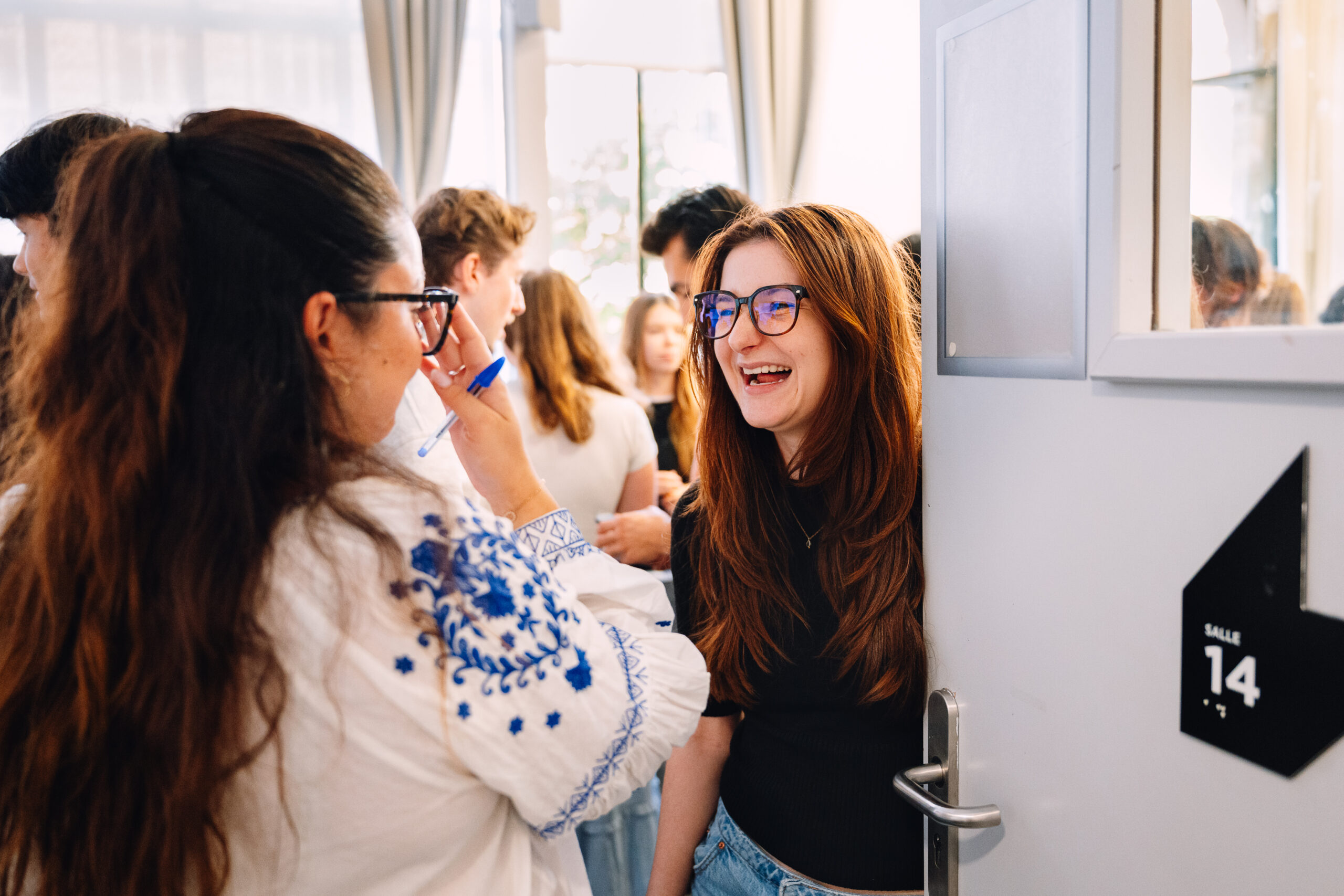 Reportage photo d'événement d'entreprise : deux participantes qui rient à l'entrée d'une salle