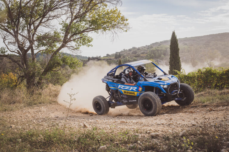 Buggy tout-terrain bleu lancé sur un chemin de terre en soulevant la poussière, reportage BF Goodrich