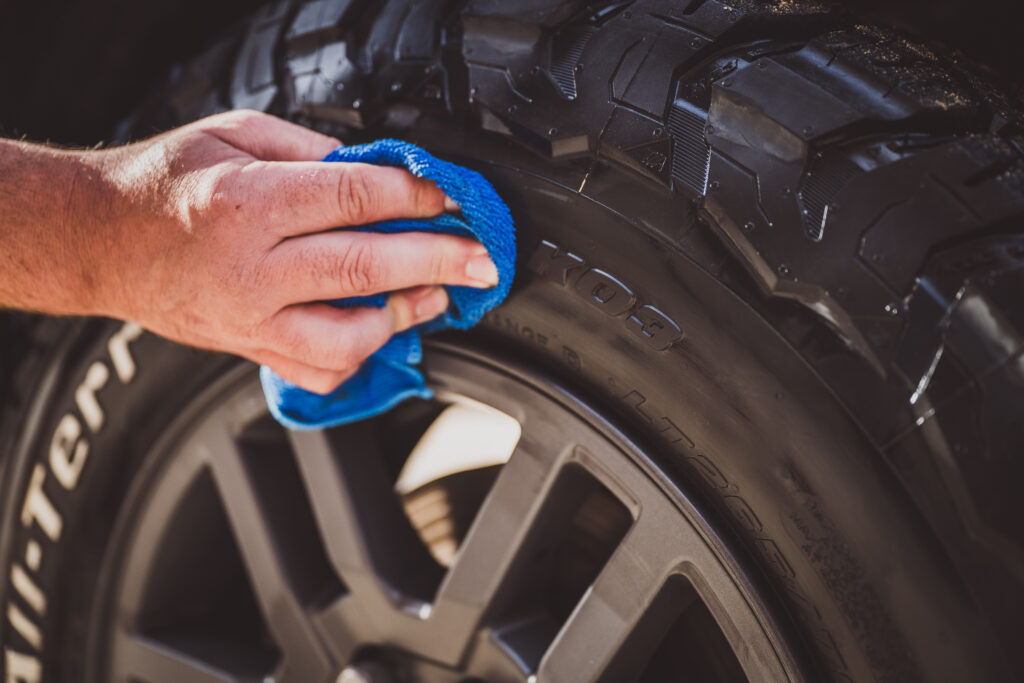 Gros plan : une main nettoie un pneu BFGoodrich tout-terrain avec un chiffon bleu