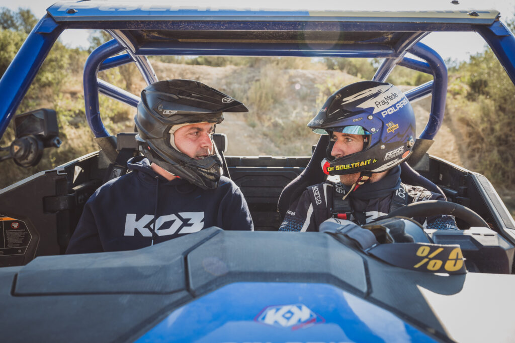 Pilote et copilote casqués échangeant un regard à bord d'un buggy bleu, reportage BF Goodrich