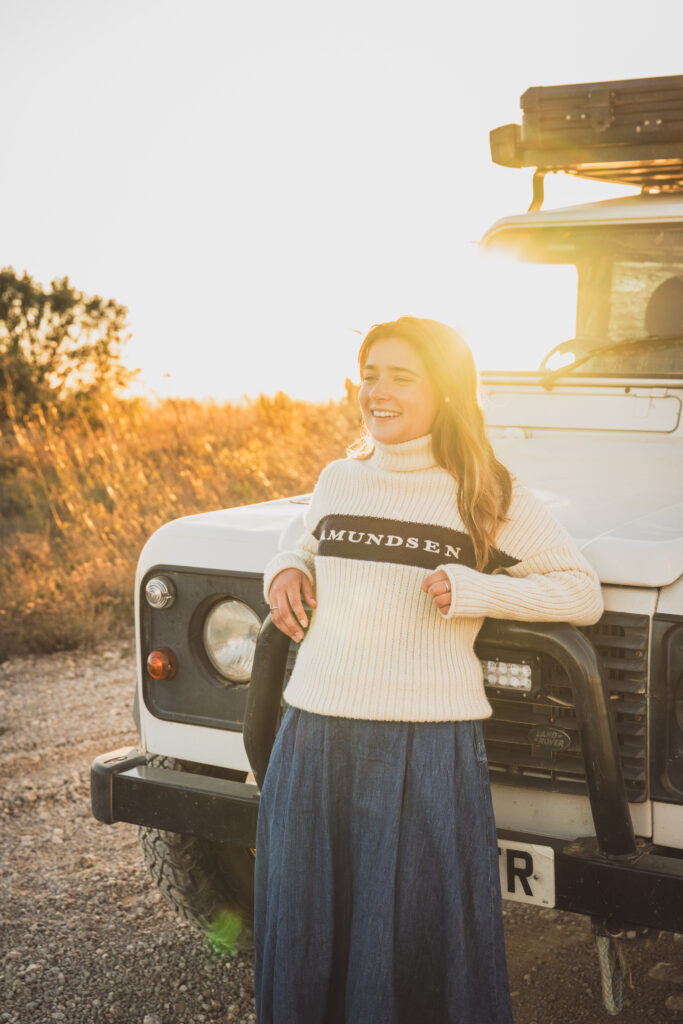 Portrait d'une femme souriante devant un 4x4 blanc à la lumière dorée, reportage BF Goodrich