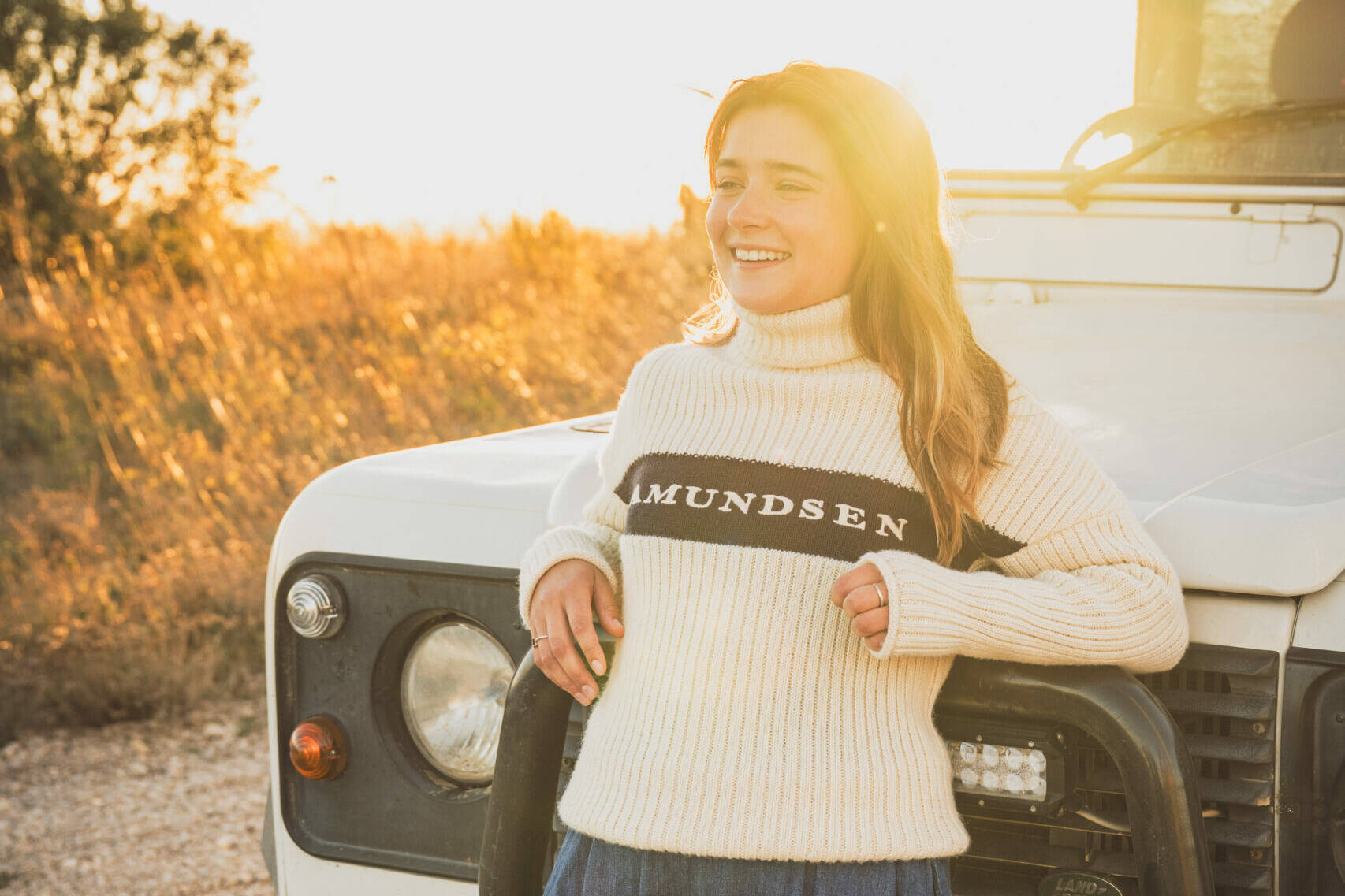 Portrait d'une femme souriante devant un 4x4 blanc à la lumière dorée, reportage BF Goodrich