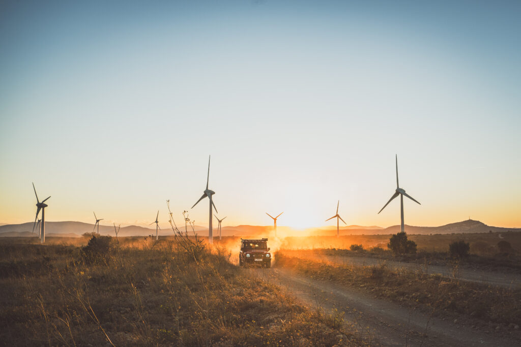 Coucher de soleil sur un champ d'éoliennes, un véhicule tout-terrain sur le chemin, reportage BF Goodrich