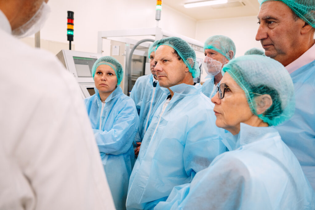 Groupe de visiteurs en blouse et charlotte à l'écoute d'une explication dans l'usine MAYOLY à Auxerre