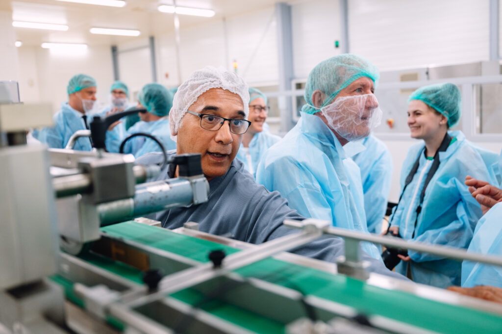 Collaborateur expliquant le fonctionnement d'une ligne de production aux visiteurs, usine pharmaceutique d'Auxerre