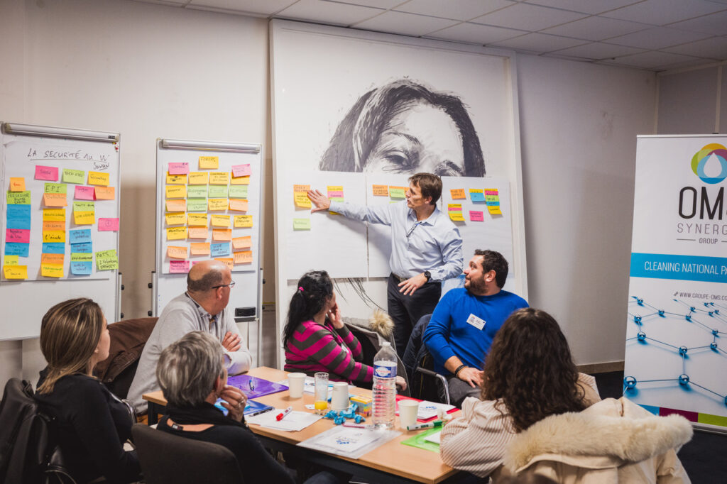OMS Synergie : salle d’atelier avec murs d’idées en post-it et kakémono OMS, séminaire de décembre 2025