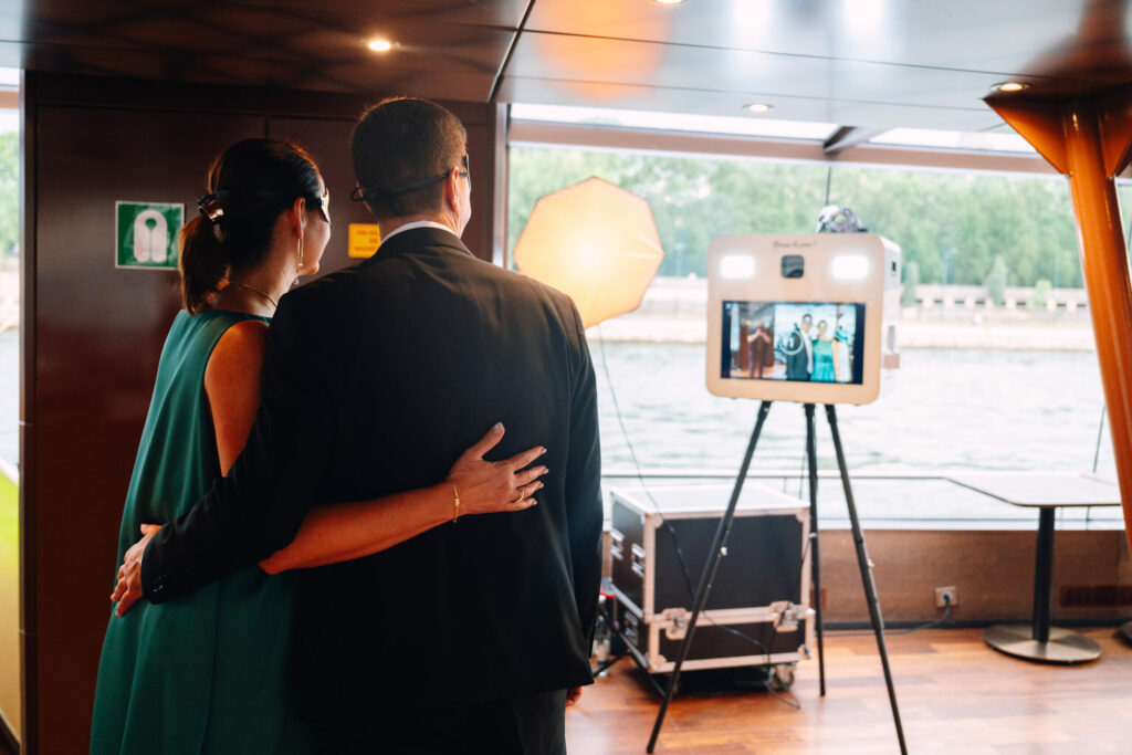 Couple prenant la pose devant le photobooth près d'une baie vitrée