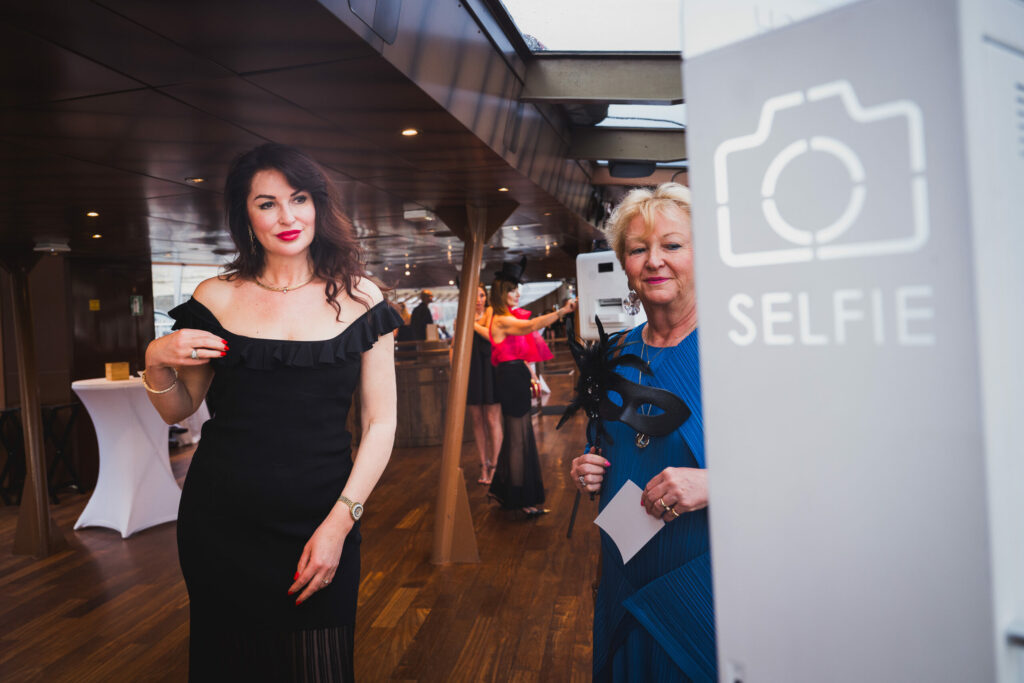 Invitée en robe noire posant devant le photobooth lors d'une soirée d'entreprise