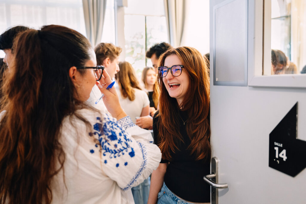 Reportage photo d'événement d'entreprise : deux participantes qui rient à l'entrée d'une salle