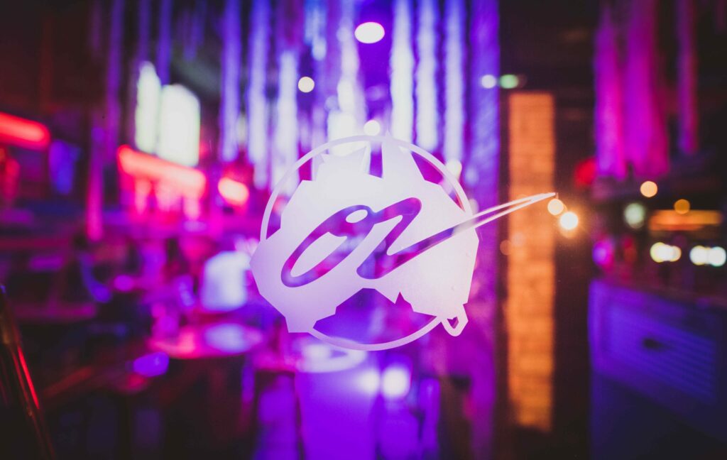 Soirée blanche au Café Oz Paris : logo Oz illuminé dans une ambiance violette