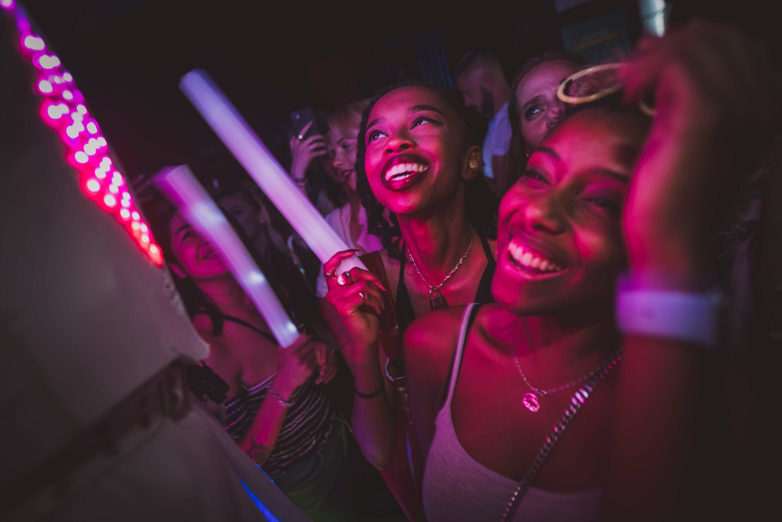 Soirée blanche au Café Oz Paris : deux fêtardes souriantes dansant avec des bâtons lumineux